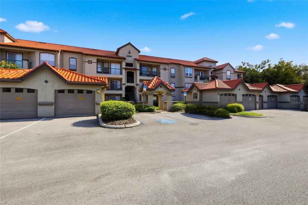 A multi-story apartment building with a tile roof and attached garages in the foreground — 4201 WOODSTORKS WALK WAY UNIT 3210, LUTZ, FL