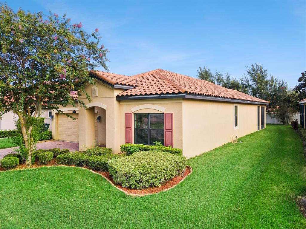A single-story house with a tan stucco exterior, red tile roof, and a manicured lawn — 1799 ALTAVISTA CIRCLE, LAKELAND, FL