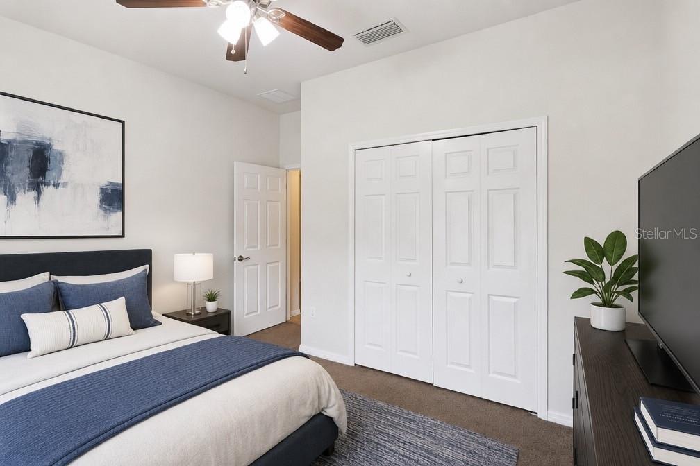 A bedroom features a bed with blue bedding, a closet with white doors, and a television — 1799 ALTAVISTA CIRCLE, LAKELAND, FL