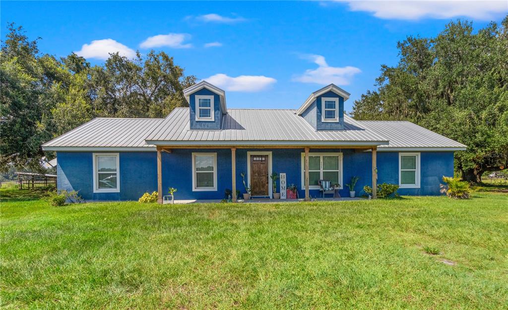 A blue one-story house with a metal roof and two dormer windows sits on grass — 3422 SR 471, SUMTERVILLE, FL
