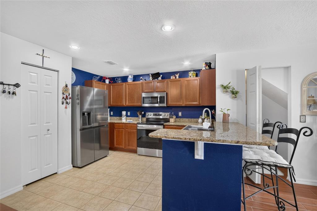 A kitchen features wood cabinets, stainless steel appliances, granite countertops, and a blue accent wall — 2919 ROYAL TUSCAN LANE, VALRICO, FL