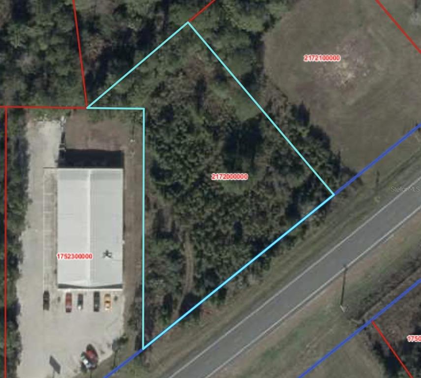 This is an aerial map showing a vacant lot outlined in blue next to a commercial building — SR 24, CEDAR KEY, FL