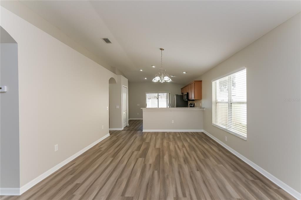 An open-concept living and dining area features wood-look flooring, a kitchen island, and recessed lighting — 15411 PEACH STONE PLACE, RUSKIN, FL