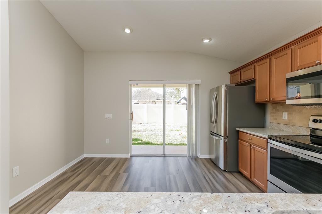 A kitchen dining area with wood-look flooring, stainless steel appliances, and a sliding glass door — 15411 PEACH STONE PLACE, RUSKIN, FL