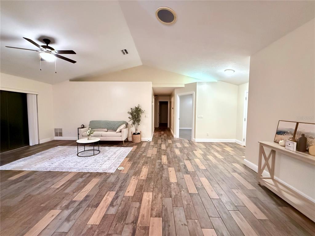 A living room features vaulted ceilings, wood-look tile flooring, and a sliding glass door — 3530 W COGWOOD CIRCLE, BEVERLY HILLS, FL