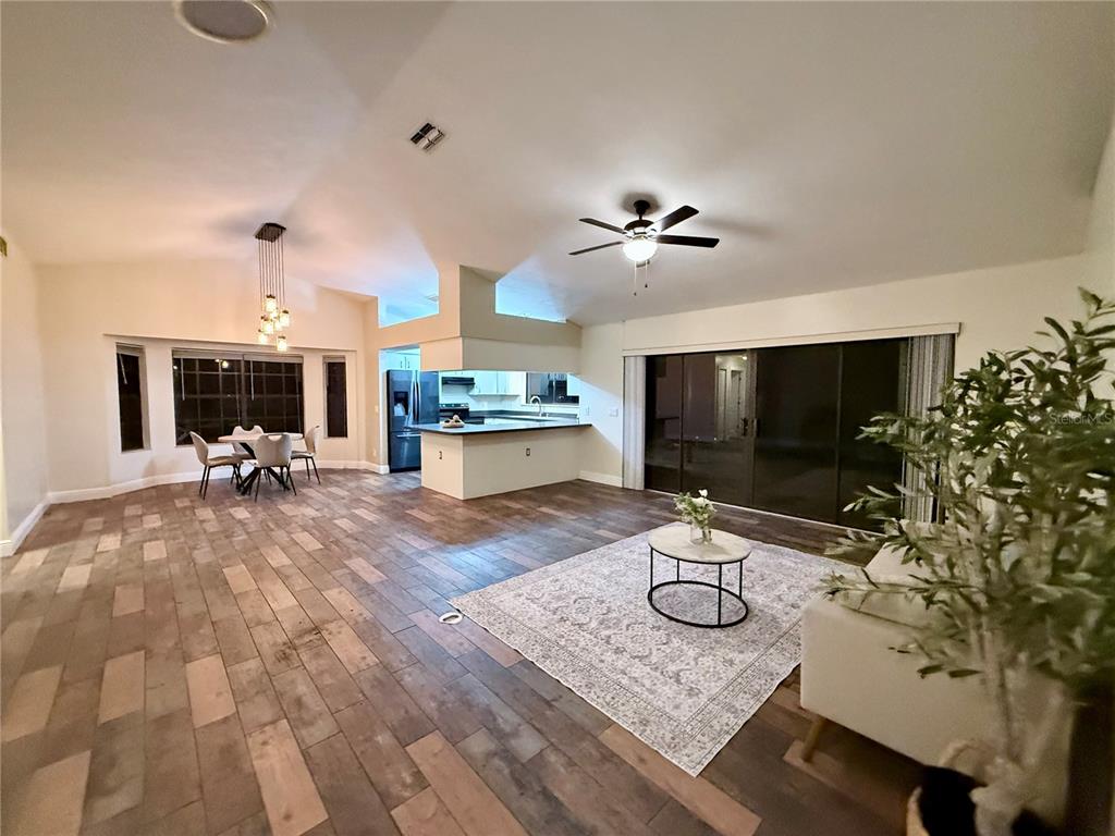 An open-concept living and dining area features wood-look tile flooring, a kitchen island, and sliding doors — 3530 W COGWOOD CIRCLE, BEVERLY HILLS, FL