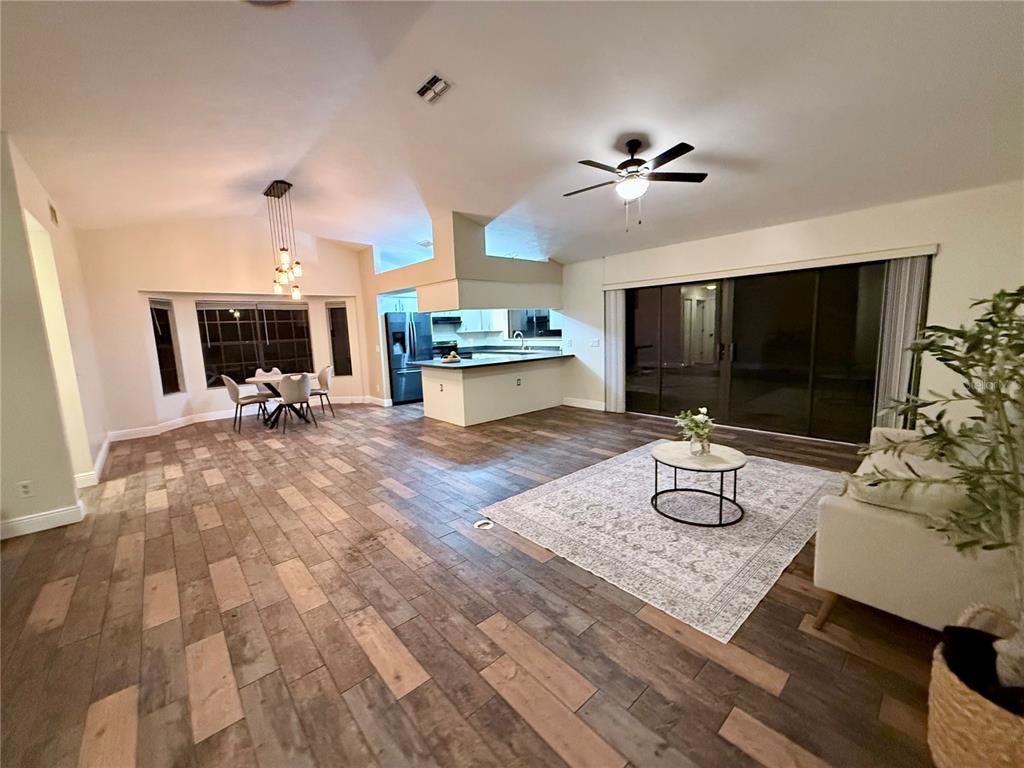 An open-concept living and dining area features wood-look tile flooring and a kitchen island — 3530 W COGWOOD CIRCLE, BEVERLY HILLS, FL