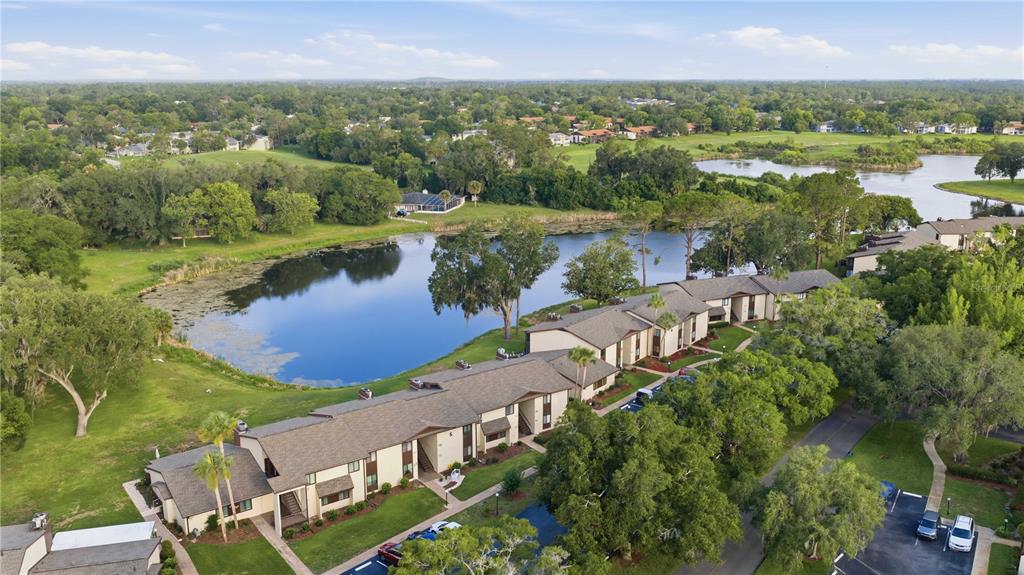 An aerial view of a multi-unit residential building situated next to a lake and trees — 681 MIDWAY DRIVE UNIT B, OCALA, FL