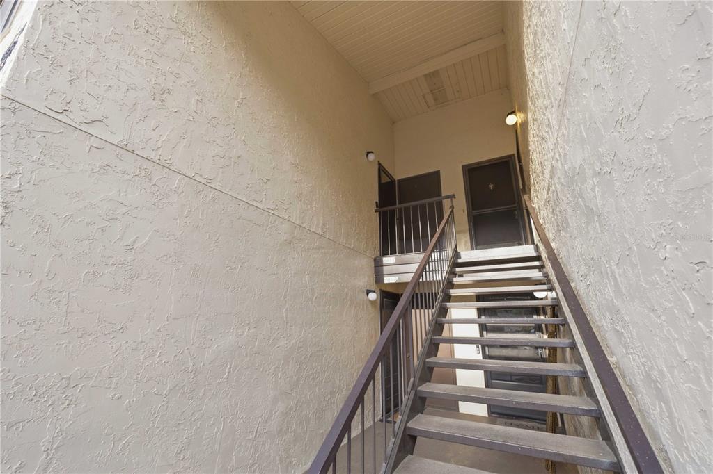 An exterior staircase leads to the entrances of two apartment units in a stucco building — 681 MIDWAY DRIVE UNIT B, OCALA, FL