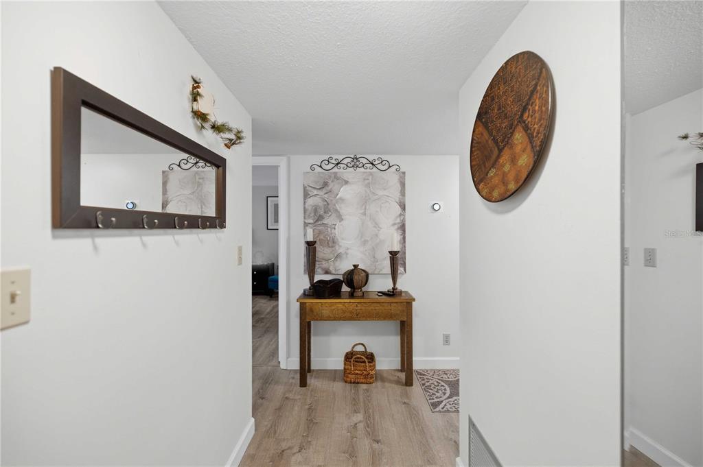A hallway features light wood-look flooring, a wooden console table, and wall-mounted decor — 681 MIDWAY DRIVE UNIT B, OCALA, FL