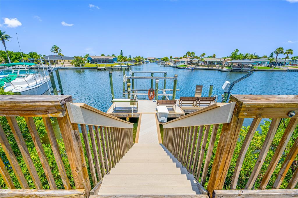A wooden staircase leads down to a private boat dock on a canal — 861 SYMPHONY ISLES BOULEVARD, APOLLO BEACH, FL
