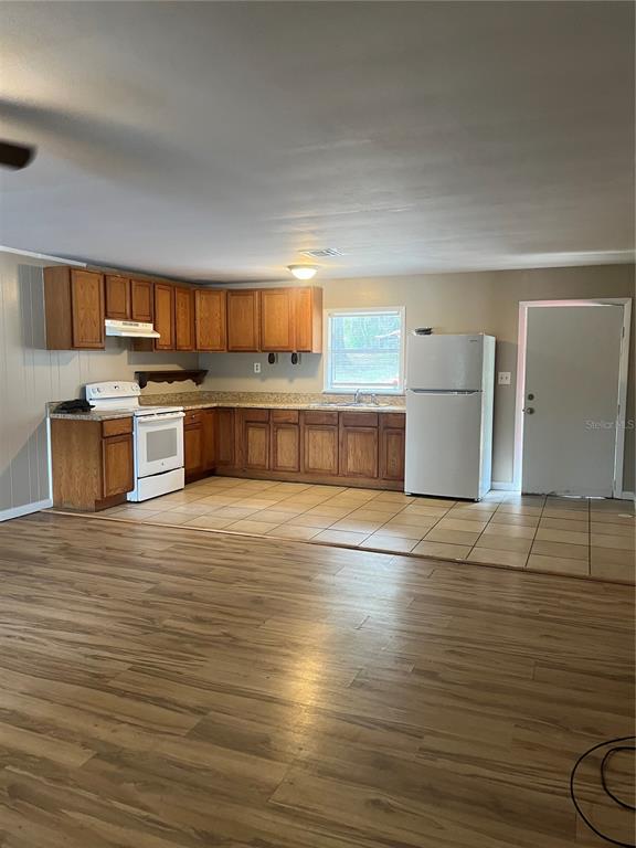 A kitchen with wood cabinets, laminate countertops, white appliances, and tile flooring — 2997 S GROVE STREET, EUSTIS, FL