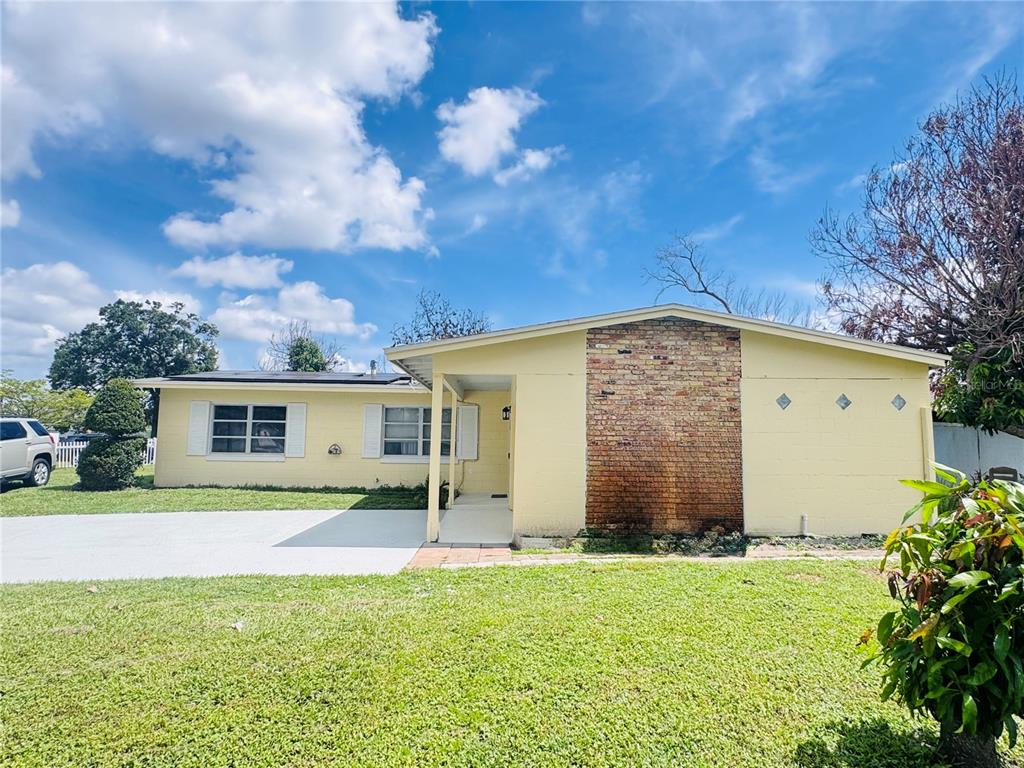 A yellow single-story house features a brick accent wall and a concrete driveway — 767 FORESTER AVENUE, ORLANDO, FL