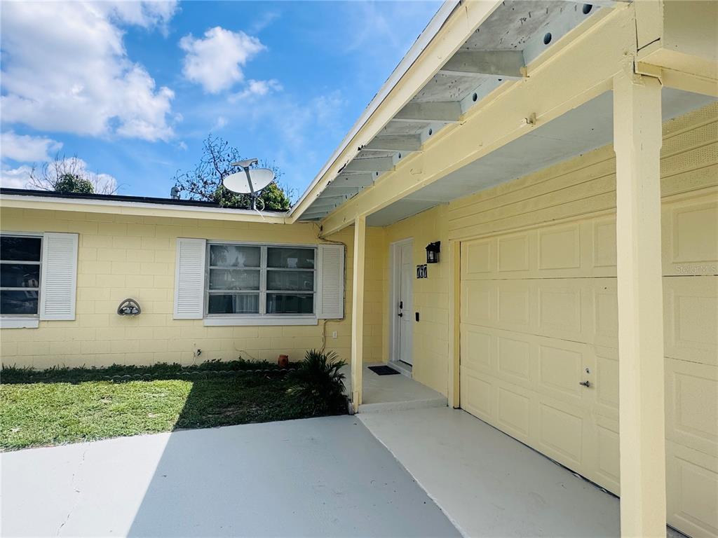 A yellow house exterior features a garage, a front door, and a small lawn — 767 FORESTER AVENUE, ORLANDO, FL