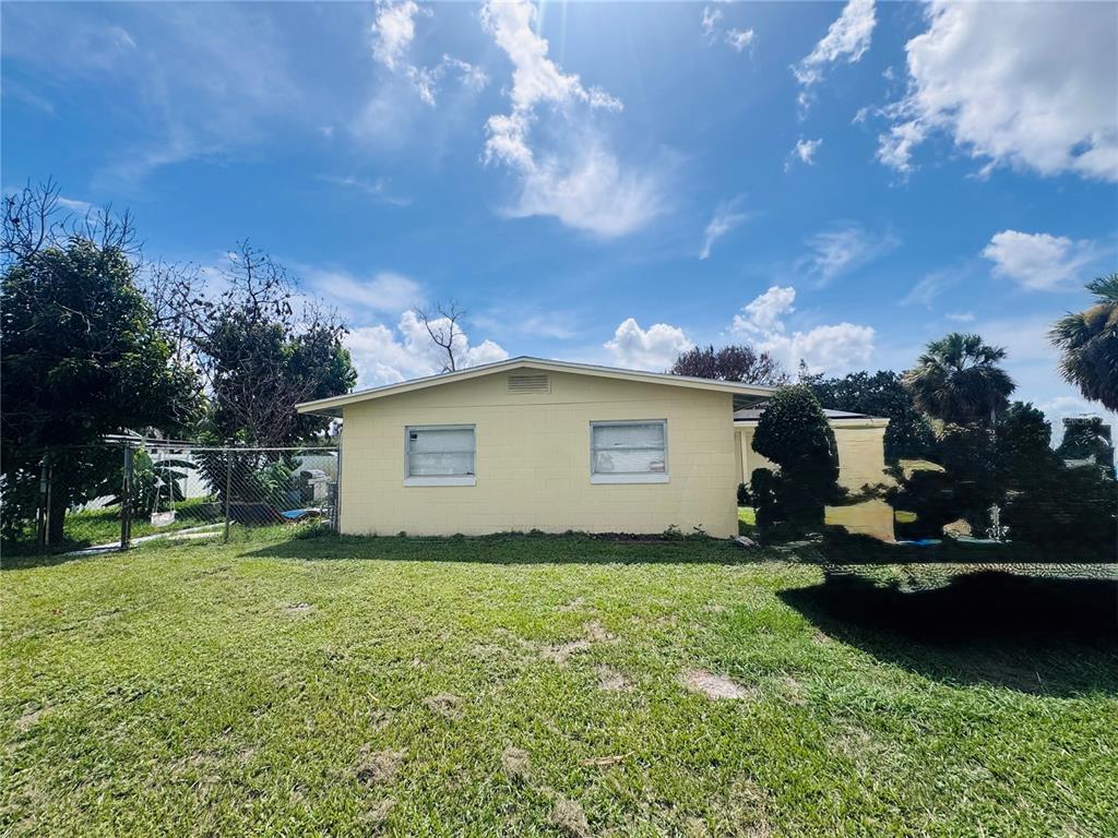 The exterior of a yellow, single-story concrete block house with two windows and a lawn — 767 FORESTER AVENUE, ORLANDO, FL