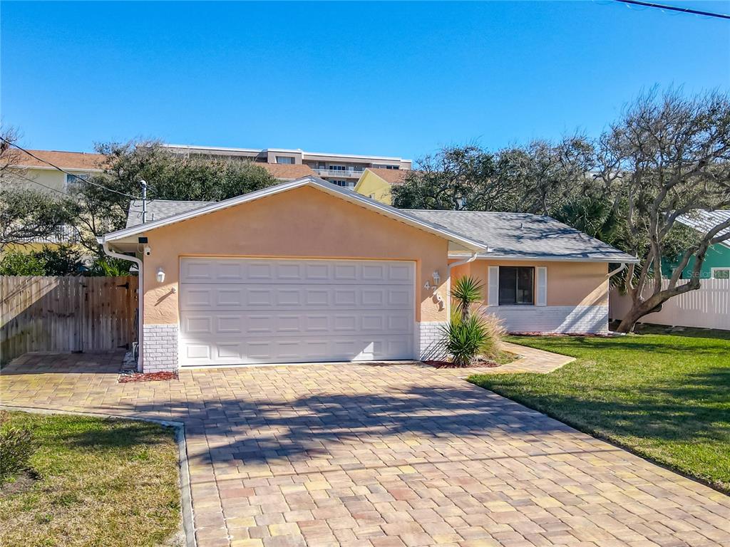 A single-story house with a peach-colored exterior, a two-car garage, and a brick paver driveway — 4761 RIVERGLEN BOULEVARD, PONCE INLET, FL