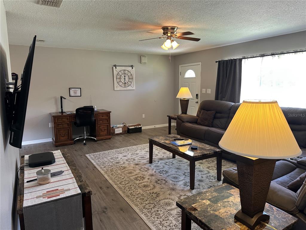 A living room features a desk, a brown sofa, a coffee table, and a ceiling fan — 3724 W SULLIVAN STREET, DUNNELLON, FL