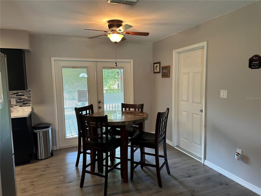 A dining area features a round table with four chairs, a ceiling fan, and glass doors — 3724 W SULLIVAN STREET, DUNNELLON, FL