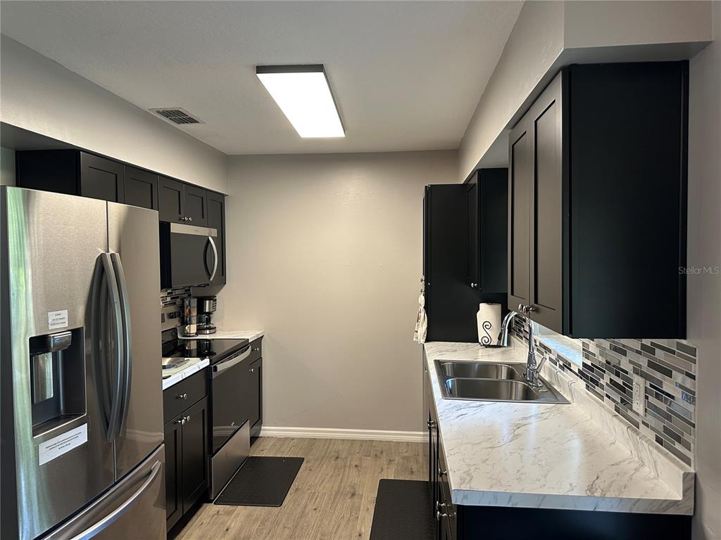 A kitchen features black cabinets, stainless steel appliances, and white marble-patterned countertops — 3724 W SULLIVAN STREET, DUNNELLON, FL