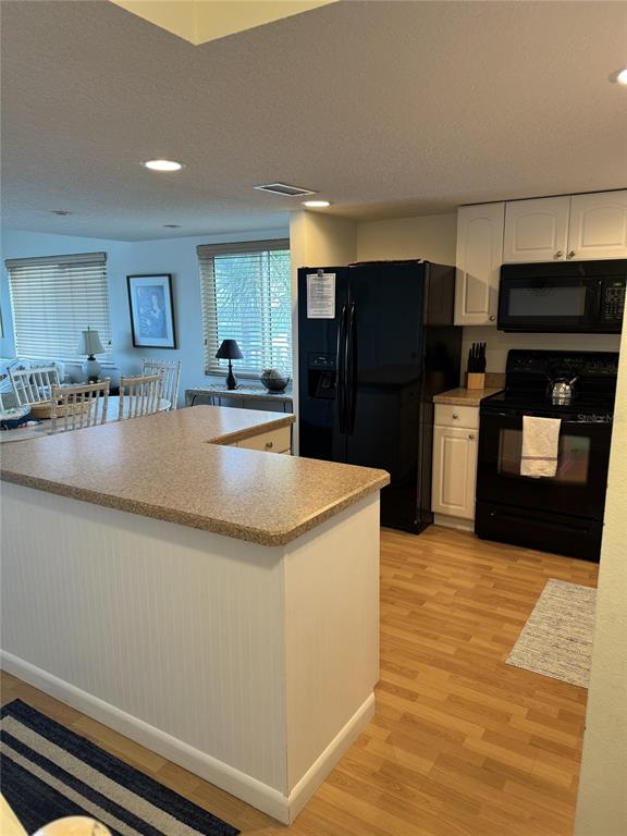 A kitchen with white cabinets, black appliances, and a tan countertop island — 815 OCEAN SHORE BOULEVARD UNIT 13A, ORMOND BEACH, FL