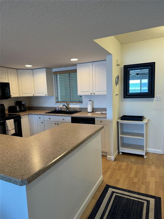 A kitchen features white cabinets, a peninsula with a speckled countertop, and a small cart — 815 OCEAN SHORE BOULEVARD UNIT 13A, ORMOND BEACH, FL