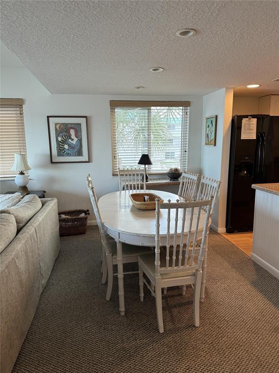 A dining area features a white oval table with four chairs on a carpeted floor — 815 OCEAN SHORE BOULEVARD UNIT 13A, ORMOND BEACH, FL