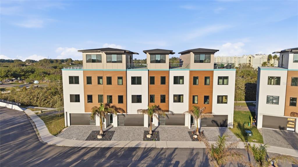 A multi-story townhouse complex features modern architecture with wood-paneled accents and attached garages — 5956 AQUA RESERVE BOULEVARD, NEW PORT RICHEY, FL