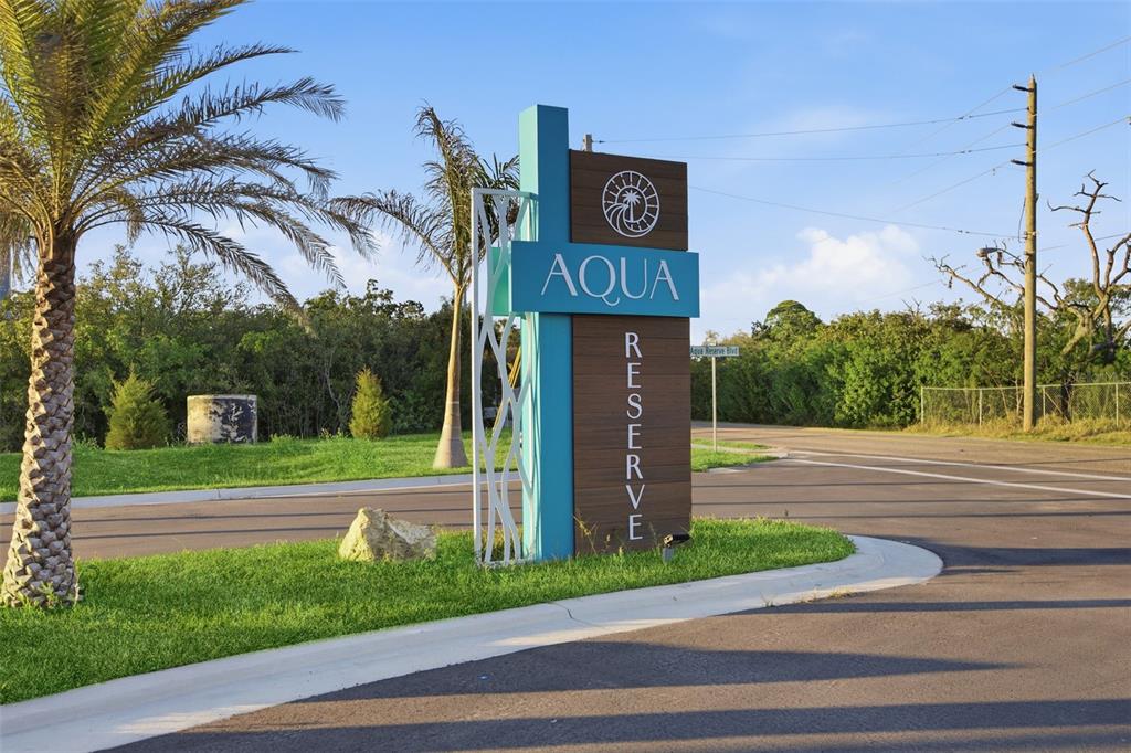A modern monument sign for Aqua Reserve stands on a grassy corner near a road — 5956 AQUA RESERVE BOULEVARD, NEW PORT RICHEY, FL