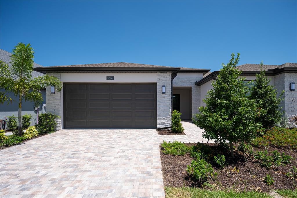 A single-story house exterior features a stone facade, a paved driveway, and a garage — 5874 WINDBREAK COURT, APOLLO BEACH, FL