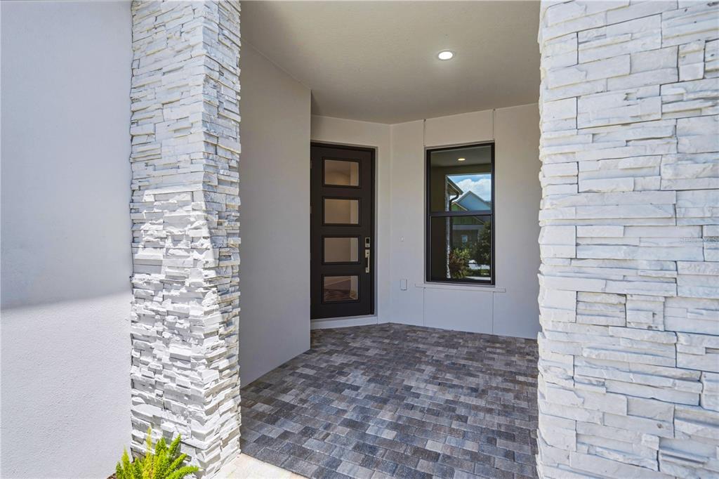 A covered entryway features a dark door, a window, and stone-clad pillars — 5874 WINDBREAK COURT, APOLLO BEACH, FL