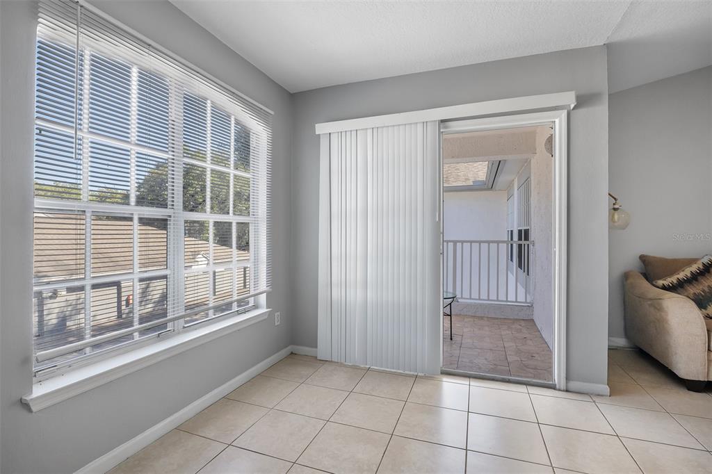 A room with light tile flooring, a large window with blinds, and a sliding glass door — 4360 S KIRKMAN ROAD UNIT 408, ORLANDO, FL