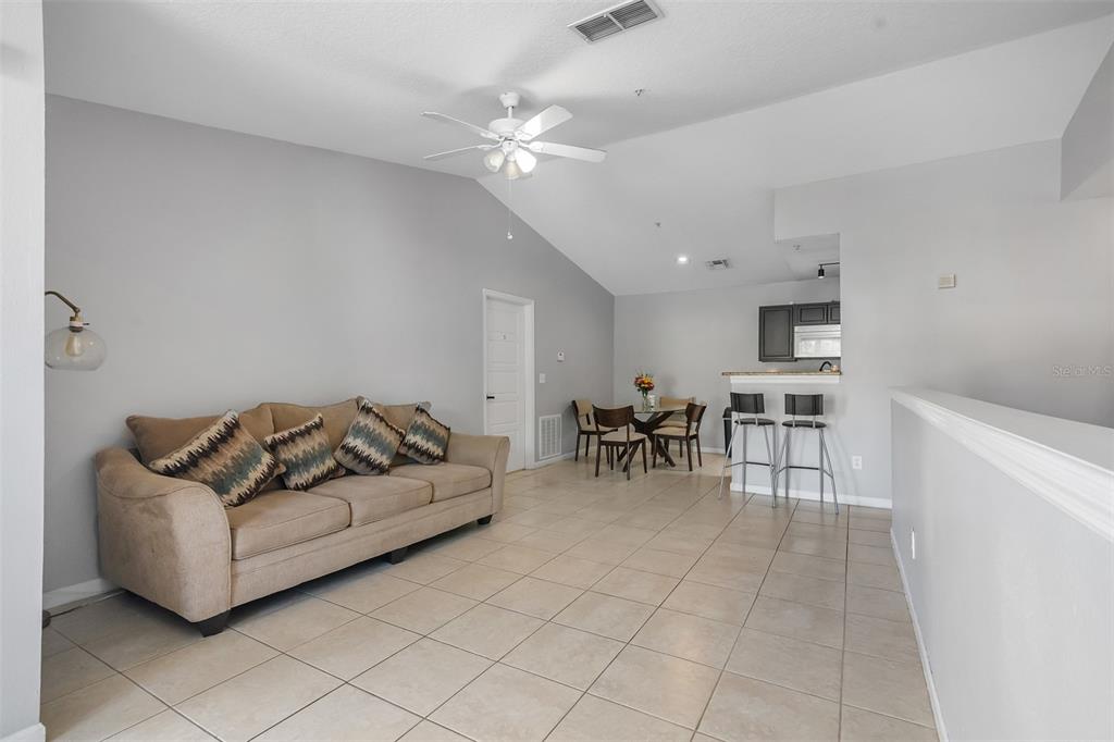 A living room with a beige sofa, tile floors, and an adjacent dining area — 4360 S KIRKMAN ROAD UNIT 408, ORLANDO, FL