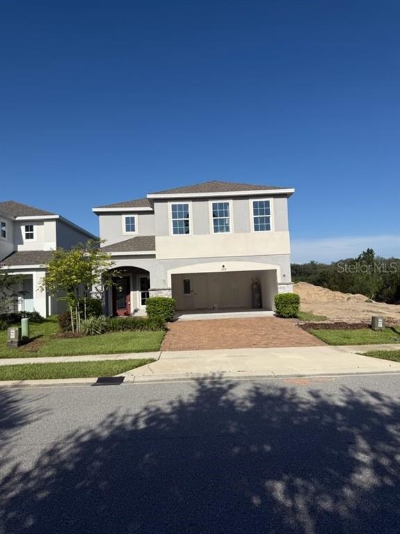 A two-story house with a brick driveway and an open garage under a clear sky — 309 PRESERVE POINTE BOULEVARD, DAVENPORT, FL