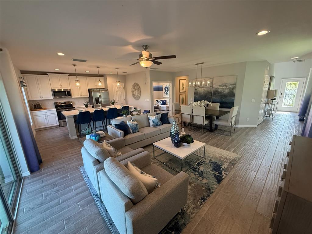 An open-concept living room and kitchen featuring light tile floors, white cabinetry, and blue accents — 309 PRESERVE POINTE BOULEVARD, DAVENPORT, FL