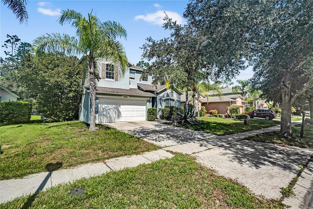 A two-story house with a light-colored stucco exterior, a two-car garage, and palm trees — 5548 ANSLEY WAY, MOUNT DORA, FL