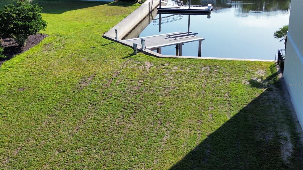 An aerial view shows a grassy backyard leading to a concrete seawall and boat dock — 243 YACHT HARBOR DRIVE, PALM COAST, FL