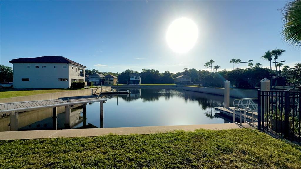 A canal view features a wooden dock, calm water, and several houses under a bright sun — 243 YACHT HARBOR DRIVE, PALM COAST, FL