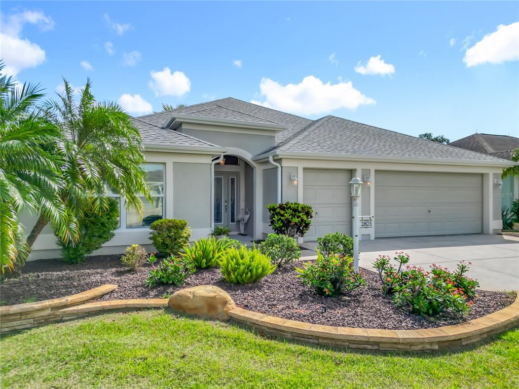A single-story house with a gray exterior, a two-car garage, and a landscaped front yard — 2875 RAIN LILY LOOP, THE VILLAGES, FL