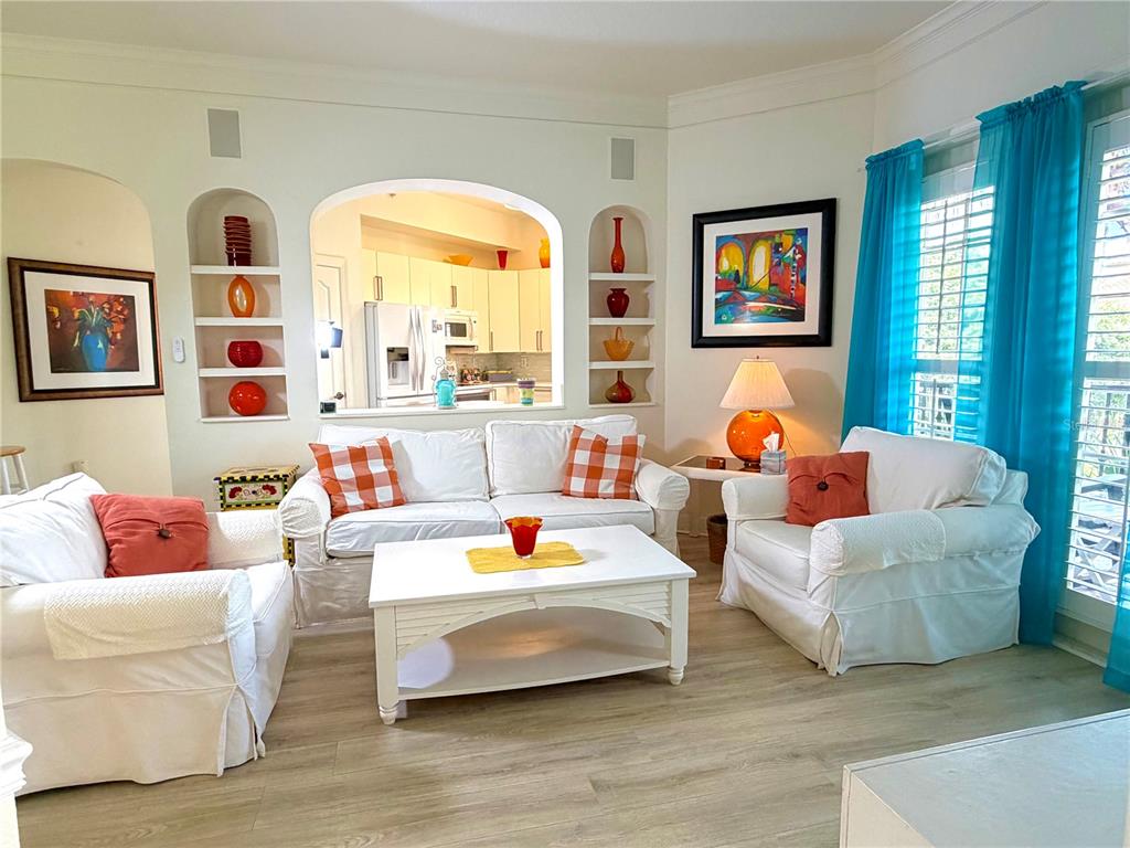 A dining area in the foreground overlooks a living room with white furniture and blue curtains — 501 MIRASOL CIRCLE UNIT 308, CELEBRATION, FL