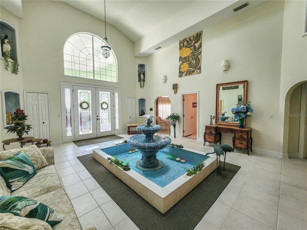 A spacious foyer features a large indoor fountain, tiled floors, and high vaulted ceilings — 1308 WICKLOW LANE, ORMOND BEACH, FL