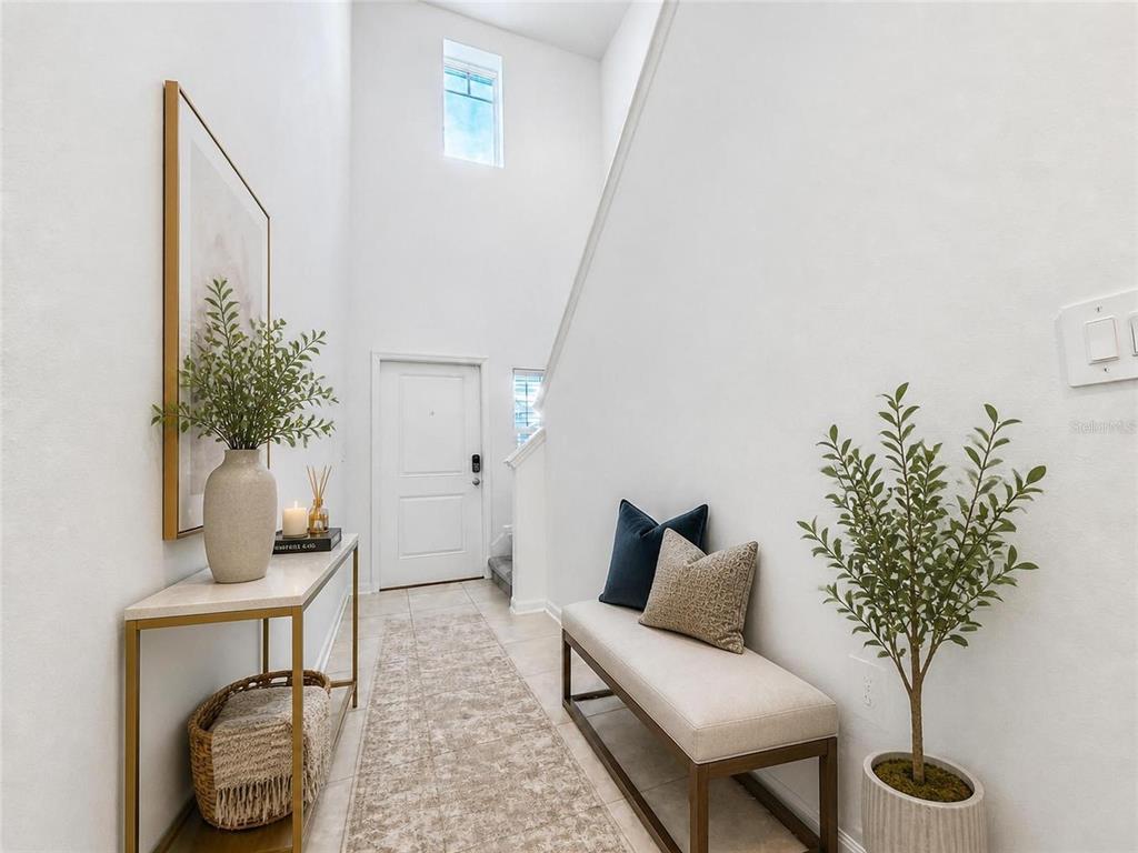 A bright entryway features a console table, a bench, and a tall staircase with windows — 809 TIMBERLAND DRIVE, EAGLE LAKE, FL