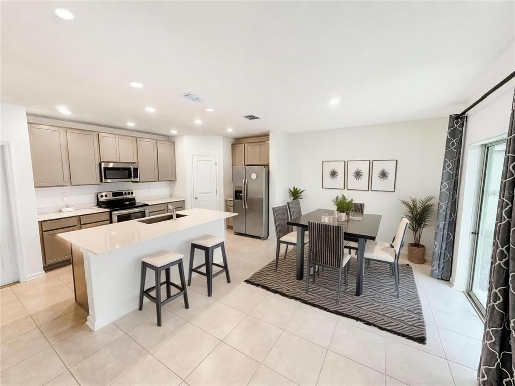 A kitchen with light-colored cabinets and a dining area with a table and chairs — 809 TIMBERLAND DRIVE, EAGLE LAKE, FL