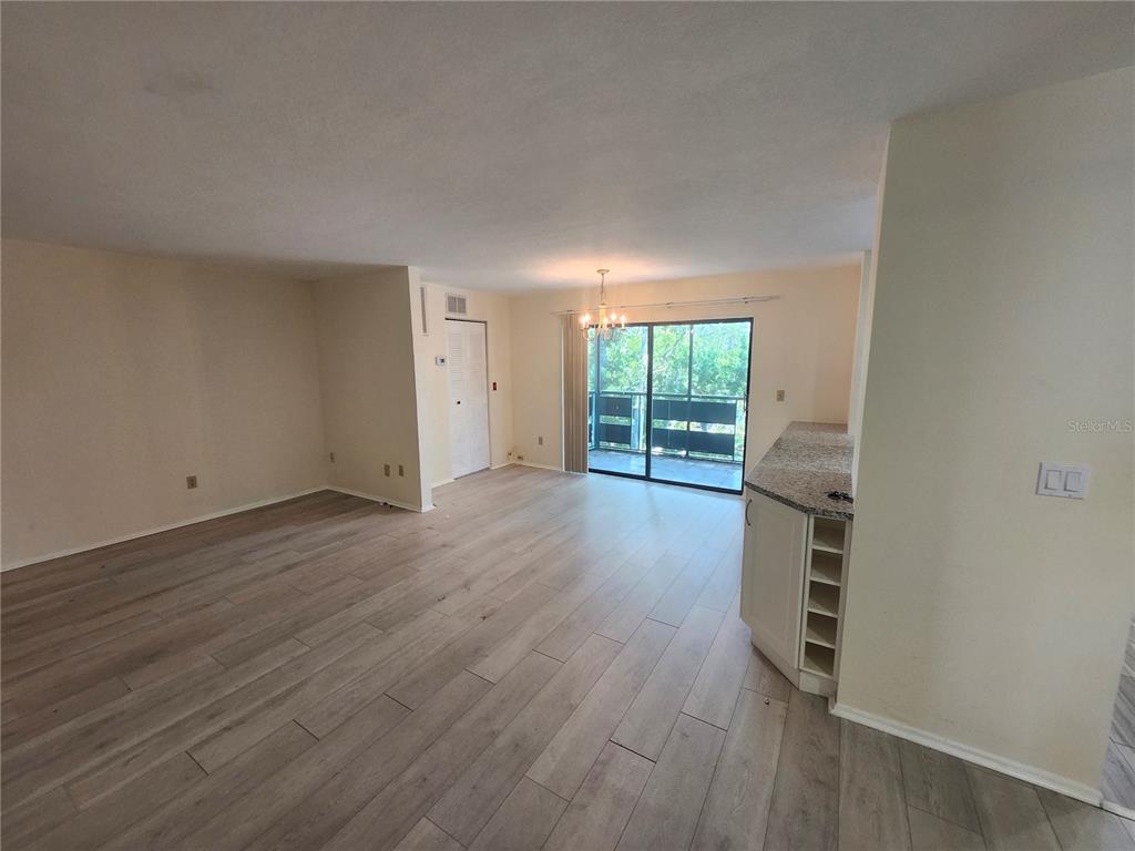 An open-concept living and dining area features light wood-look flooring and a kitchen island — 5970 80TH STREET N UNIT 409, ST PETERSBURG, FL