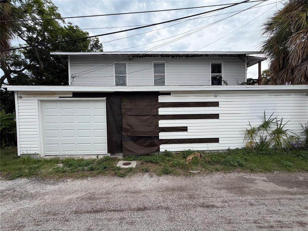 A two-story building features a white garage door and exterior siding with dark fabric panels — 614 15TH STREET N, ST PETERSBURG, FL