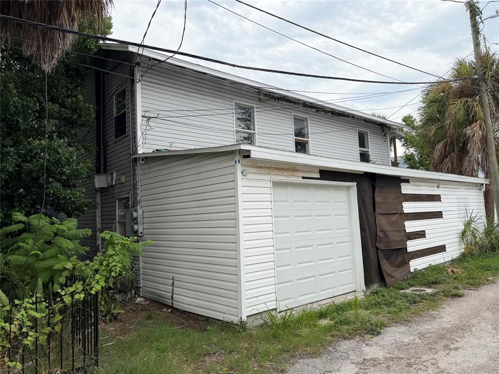 A two-story house with white siding and an attached garage sits next to a gravel path — 614 15TH STREET N, ST PETERSBURG, FL