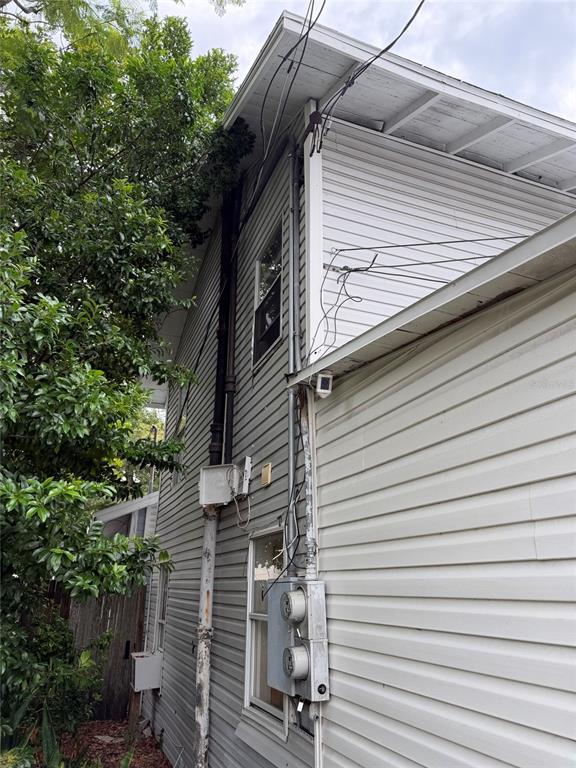 The exterior side of a house features vinyl siding, electrical meters, and utility wiring — 614 15TH STREET N, ST PETERSBURG, FL