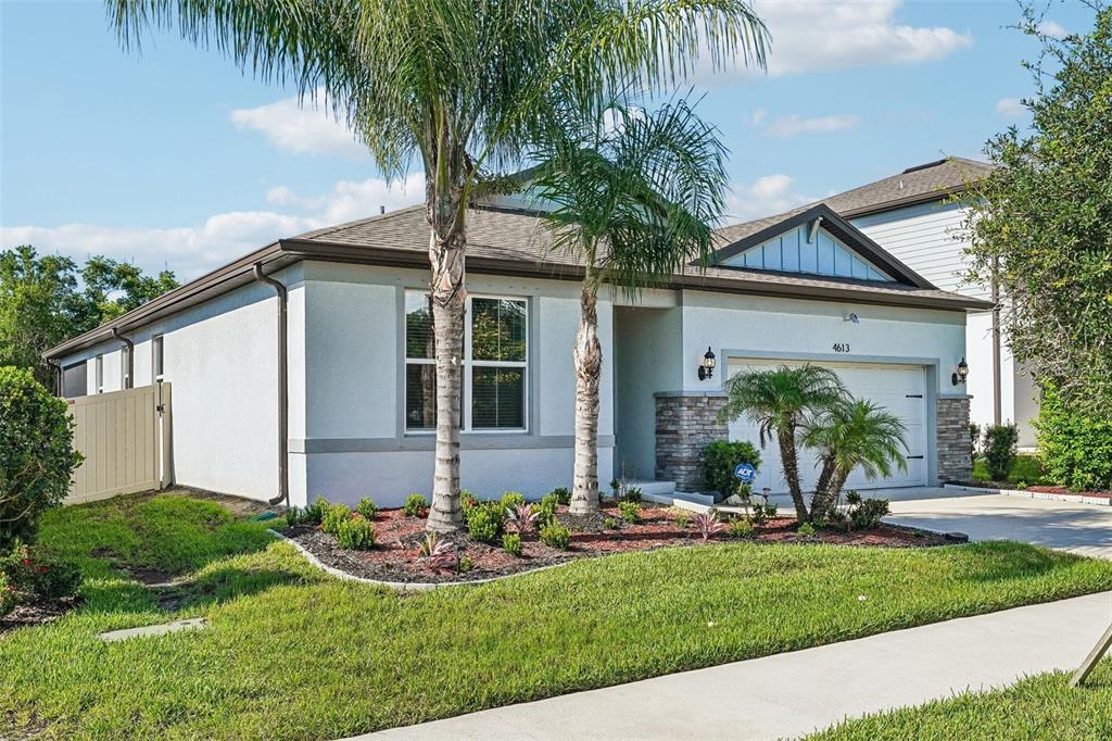 A single-story house with a light-colored stucco exterior, a two-car garage, and palm trees — 4613 DOVER BLUFF COURT, VALRICO, FL