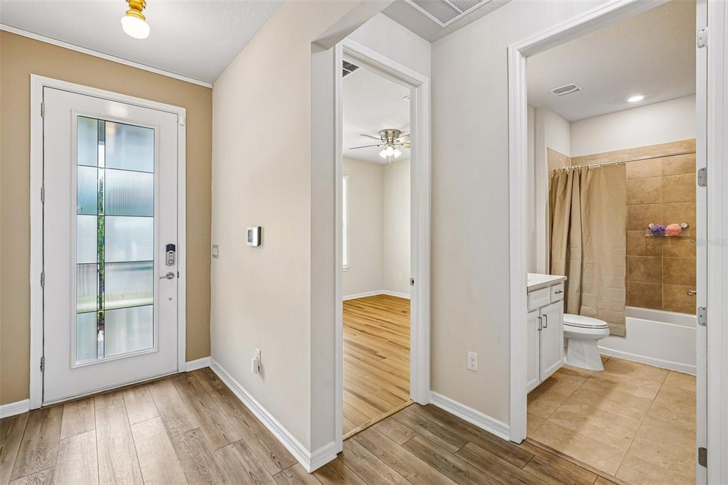 An entryway with wood-look flooring leads to a bedroom and a bathroom with a shower — 4613 DOVER BLUFF COURT, VALRICO, FL
