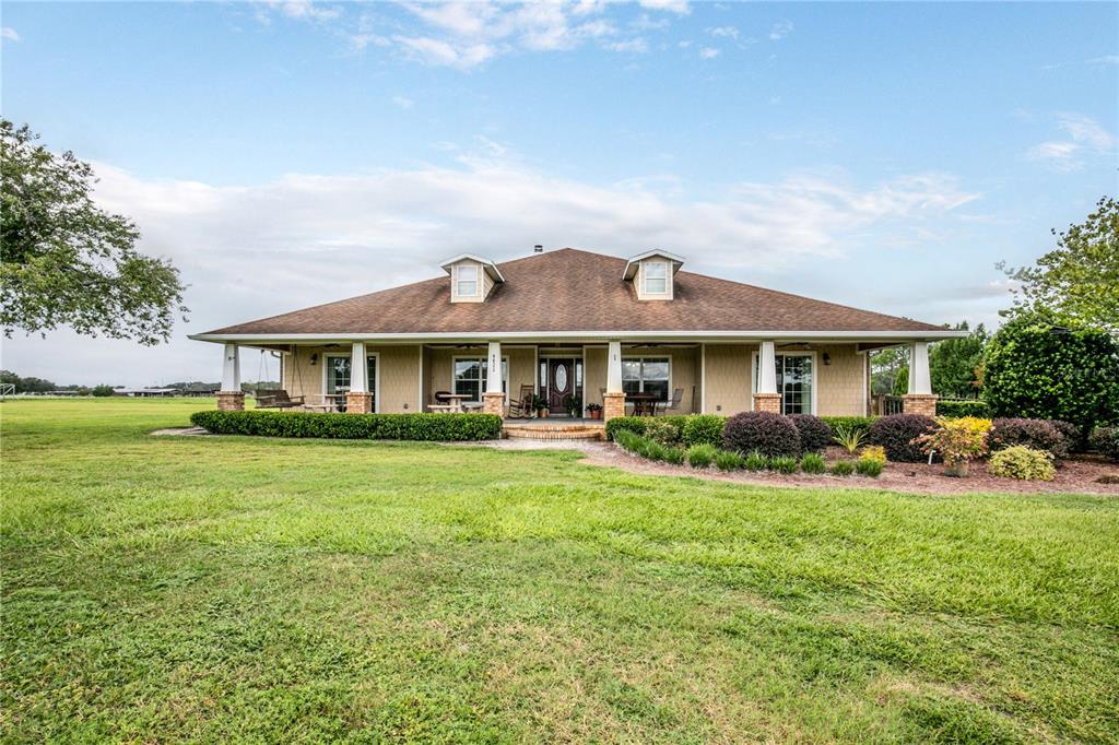 A single-story house with a wrap-around porch, dormer windows, and a large grassy yard — 6622 SR 471, BUSHNELL, FL