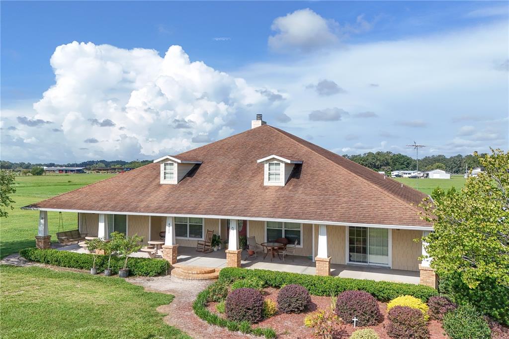 An aerial view of a single-story house with a wrap-around porch and two dormer windows — 6622 SR 471, BUSHNELL, FL